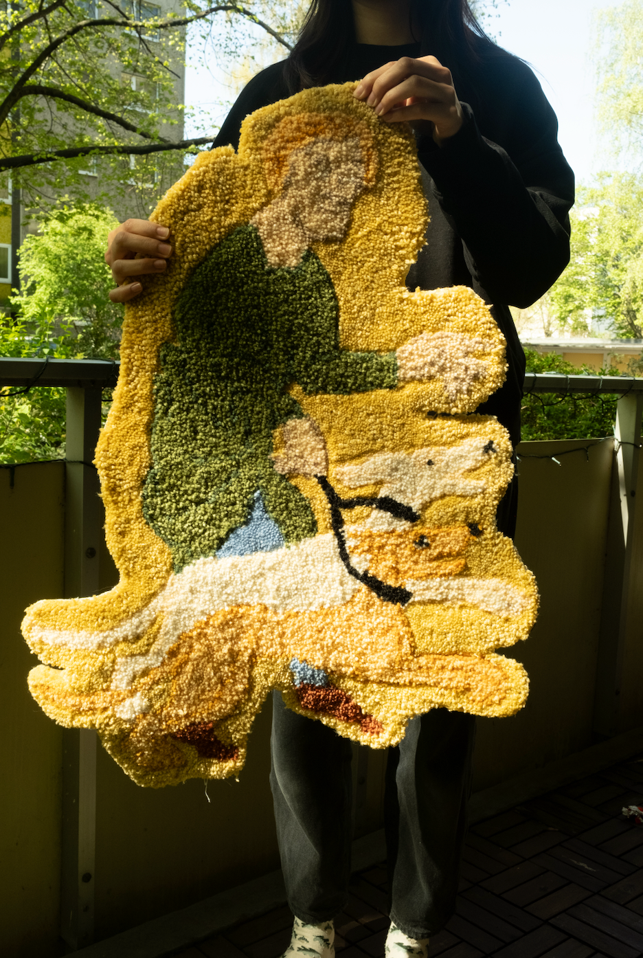 Person holding a textured, multicolored rug outdoors