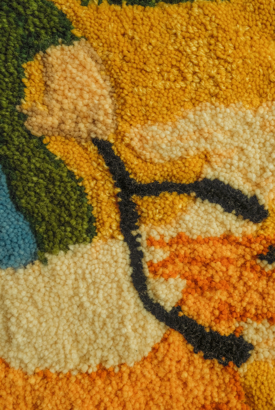 Close-up of a handmade tufted rug cut pile in orange, green, and beige